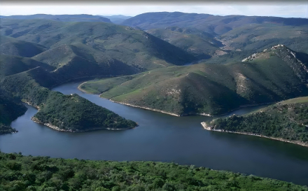Vista del Parque Nacional de Monfragüe con buitres volando sobre las montañas.