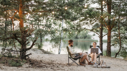 Pareja de camping que trabaja con ordenador - Generadores eléctricos para minicaravanas