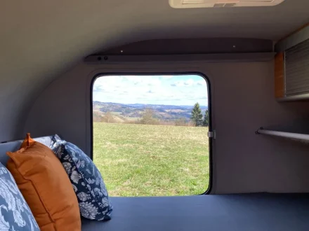 Interior de una caravana con ventana abierta al paisaje, mostrando confort y buena temperatura interior.