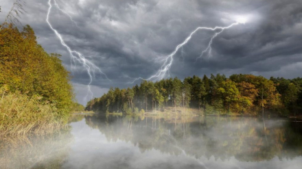 Tormenta eléctrica en la naturaleza, con nubes y rayos reflejados en un lago tranquilo.