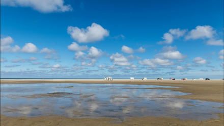Playa con caravanas y autocaravanas aparcadas cerca de la orilla, en zona de acampada autorizada