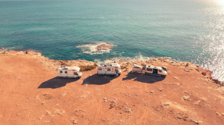 Vista aérea de vehículos junto al mar con placas solares desplegadas para cargar baterías