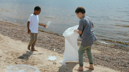 niños recogiendo plástico en la playa durante un voluntariado ambiental