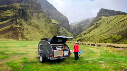 Minicaravana Caretta 1500 en alta montaña con una viajera disfrutando del paisaje.